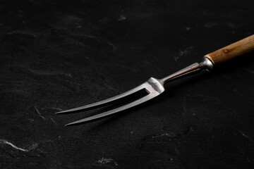 Meat fork close-up on a black background.