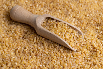 Not cooked wheat porridge with a wooden spoon