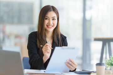 Fototapeta premium Attractive asia busy business woman consultant auditor working at modern office with balance sheet accounting bookkeeping documents. Account verification to prevent fraud bribery.