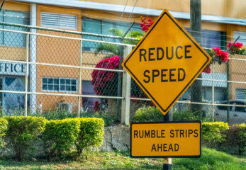 A yellow reduce speed sign on a road