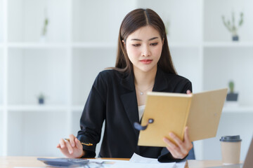 Attractive asia busy business woman consultant auditor working at modern office with balance sheet accounting bookkeeping documents. Account verification to prevent fraud bribery.