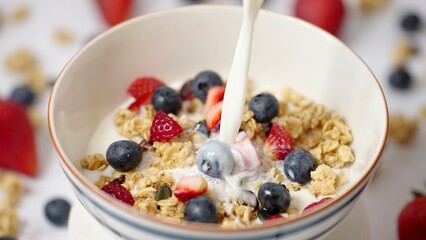 Milk pouring in bowl of healthy breakfast crunchy Granola Cereals with stawberry , blueberry vegan food, clean eating, dieting concept