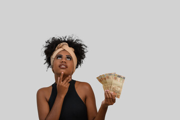 thoughtful woman with money, young afro woman with brazilian money, advertising concept on gray background