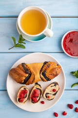 Sweet bun with strawberry jam on a blue wooden background, top view, close up.