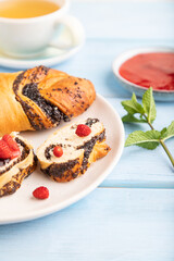 Sweet bun with strawberry jam on a blue wooden background, side view, selective focus.