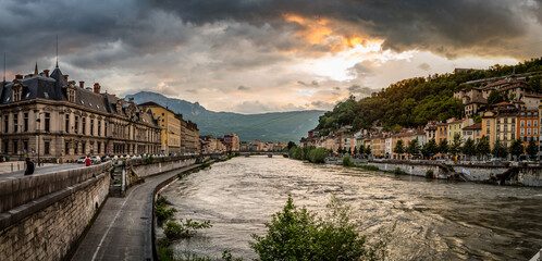 Panorama with a dramatic sunset looking down the Isere river towards the old section of Grenoble France