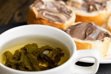 Green tea brewed in a mug and a baguette with chocolate butter