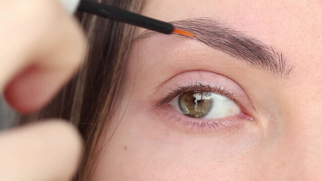 Eyebrow Serum for Women. An open-eyed girl applying a serum with essential oils and peptides to her eyebrows for strong growth, density and problem solving. Close-up.