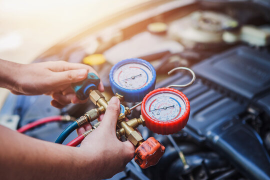 An Auto mechanic  Worker hands  holding  monitor to check and fixed car air conditioner system in  car garage with copy space