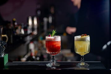 Two cocktails red and yellow on the bar.