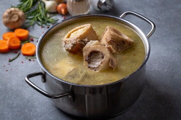 Boiled bone and broth. Homemade beef bone broth is cooked in a pot on. Bones contain collagen, which provides the body with amino acids, which are the building blocks of proteins. - obrazy, fototapety, plakaty