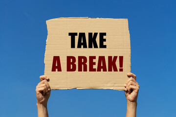 Take a break text on box paper held by 2 hands with isolated blue sky background. This message...