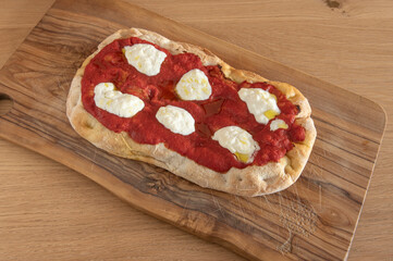 A piece of Pinsa Romana, a traditional Italian pizza with tomato, stracciatella cheese , burrata...