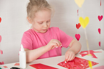 children's applications for valentine's day, the girl cuts out valentines and makes cards for the holiday