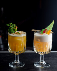 Two Yellow cocktail with foam on a dark background