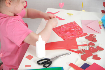 children's applications for valentine's day, the girl cuts out valentines and makes cards for the holiday