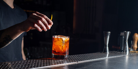 Bartender makes an orange cocktail with citrus fruits.