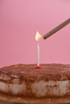 Image of a candle lighting up on a cake decorated with chocolate, copy space