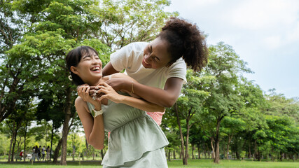 Portrait of happy young multi racials girlfriends ladies hugging and playing  outdoors on the park...