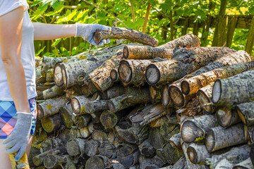 man piles firewood in a pile in the garden