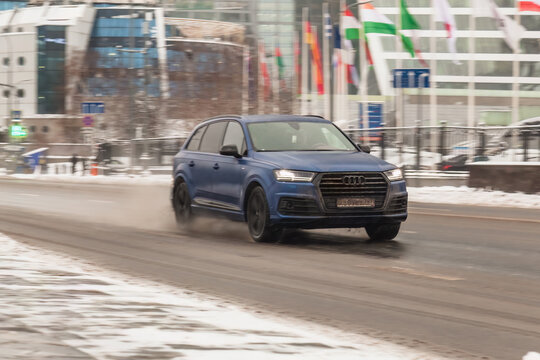 Audi Q7 car drive down a wet slippery city street. Blue suv in motion blur on winter road