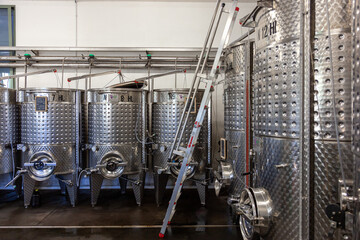 Interno di cantina per vinificazione, viticoltura, affinamento e creazione del mosto. Cisterne in acciaio in ambiente industriale.