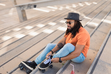 Black man enjoy outside. Modern man posing with roller skates..