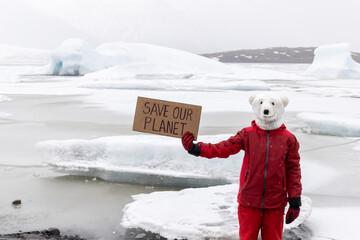Earth day, polar bear masked activist holds banner Save Our Planet next to glacier