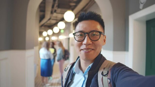 Happy asian man student talking to camera holding phone recording vlog. Realtime