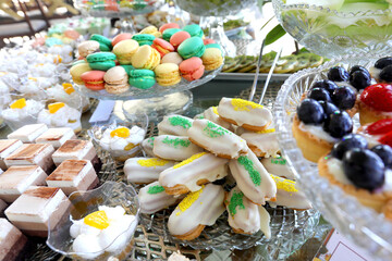 Close up of white chocolate eclairs along with several platters of different cakes