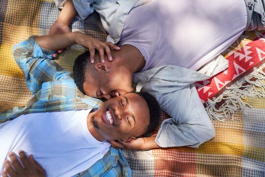 High angle view happy young gay male couple kissing on blanket