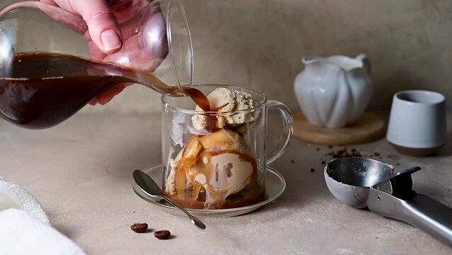 Pouring espresso coffee on ice cream scoop in glass cup Affogato Italian dessert