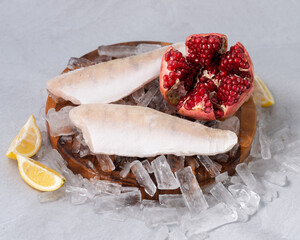frozen fresh fish, seafood on a wooden board on the ice on a gray rock background