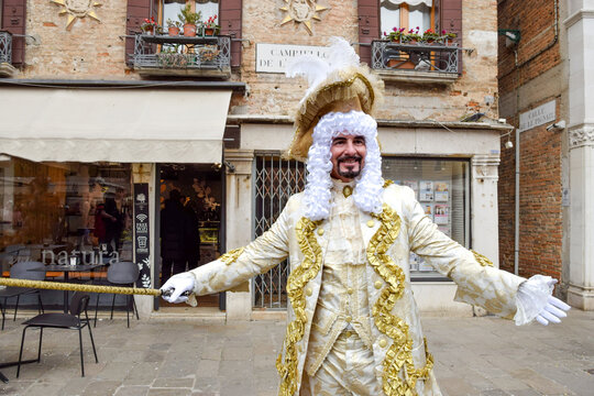 Person dressed up for Carnival of Venice wearing golden clothes