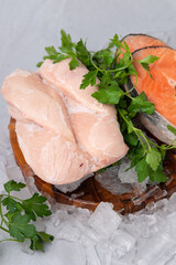 raw salmon steak with herbs and raw chicken breast on the wooden board on a gray rock background , raw ingredient for healthy diet, lunch, dinner, break7 uncooked frozen chicken and salmon