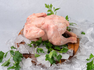 frozen raw chicken with vegetables on the ice on wooden board on the.gray rock background