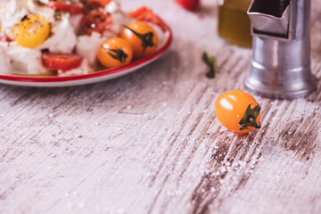 Yellow Cherry tomato and caprese salad in the background on a kitchen table