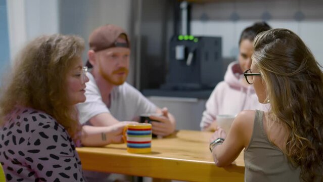 Happy young people friends talking laughing in kitchen. Realtime