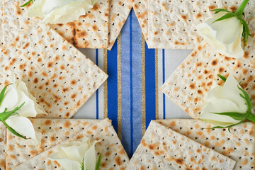 Passover celebration concept. Blue Star of David made from matzah, white and yellow roses, kippah...