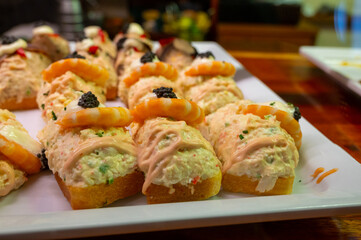 Typical snack of Basque Country, pinchos or pinxtos, small piece of bread with different fish and sea food toppings, served in bar in San-Sebastian or Bilbao, Spain