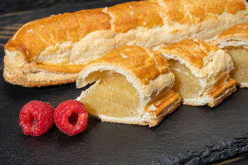 Fresh baked Dutch filled spicy cookies from puff pastry with almonds in autumn colors on dark stone