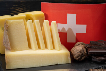 Assortment of Swiss cheeses Emmental or Emmentaler medium-hard cheese with round holes, Gruyere, appenzeller used for traditional cheese fondue and gratin and flag of Switzerland
