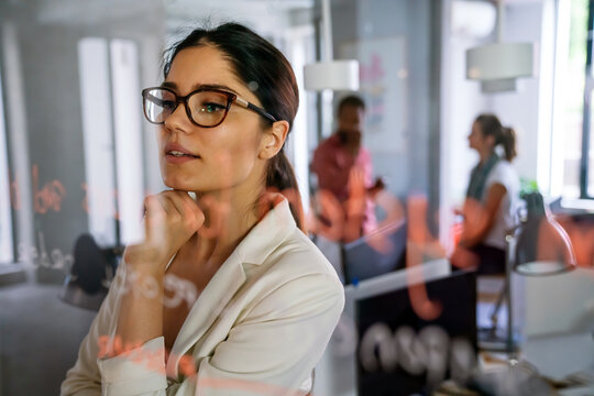 Woman working and writing on the glass board in office. Business, technology, research concept