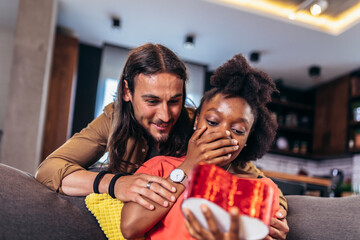 Surprised woman opening a present her boyfriend bought her for their anniversary.