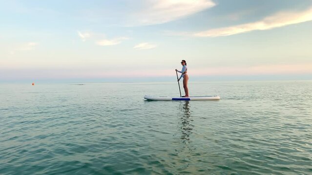 Woman paddleboarder enjoying relaxing floating in calm sea