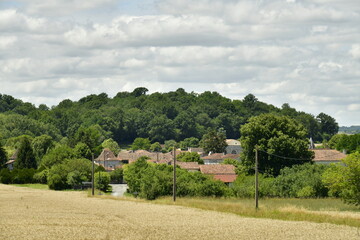 Le bourg de Champagne devant une colline boisée sous un ciel nuageux ,au Périgord Vert 