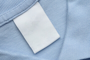 White blank laundry care clothes label on blue shirt fabric background