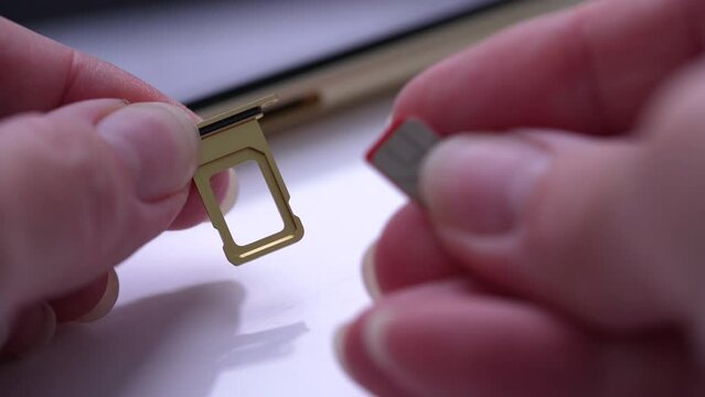 Person inserting a sim card into back of mobile phone, Sim card in tray being inserted into phone