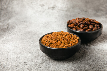 Instant coffee grains and coffee beans in bowls on a black marble background. Hot drink ingredients. Instant coffee on the table. Espresso. Place for text. Place to copy. Banner.