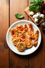 Piatto con manicaretti di pasta sfoglia conditi con mozzarella, pomodoro e pancetta, antipasto italiano 